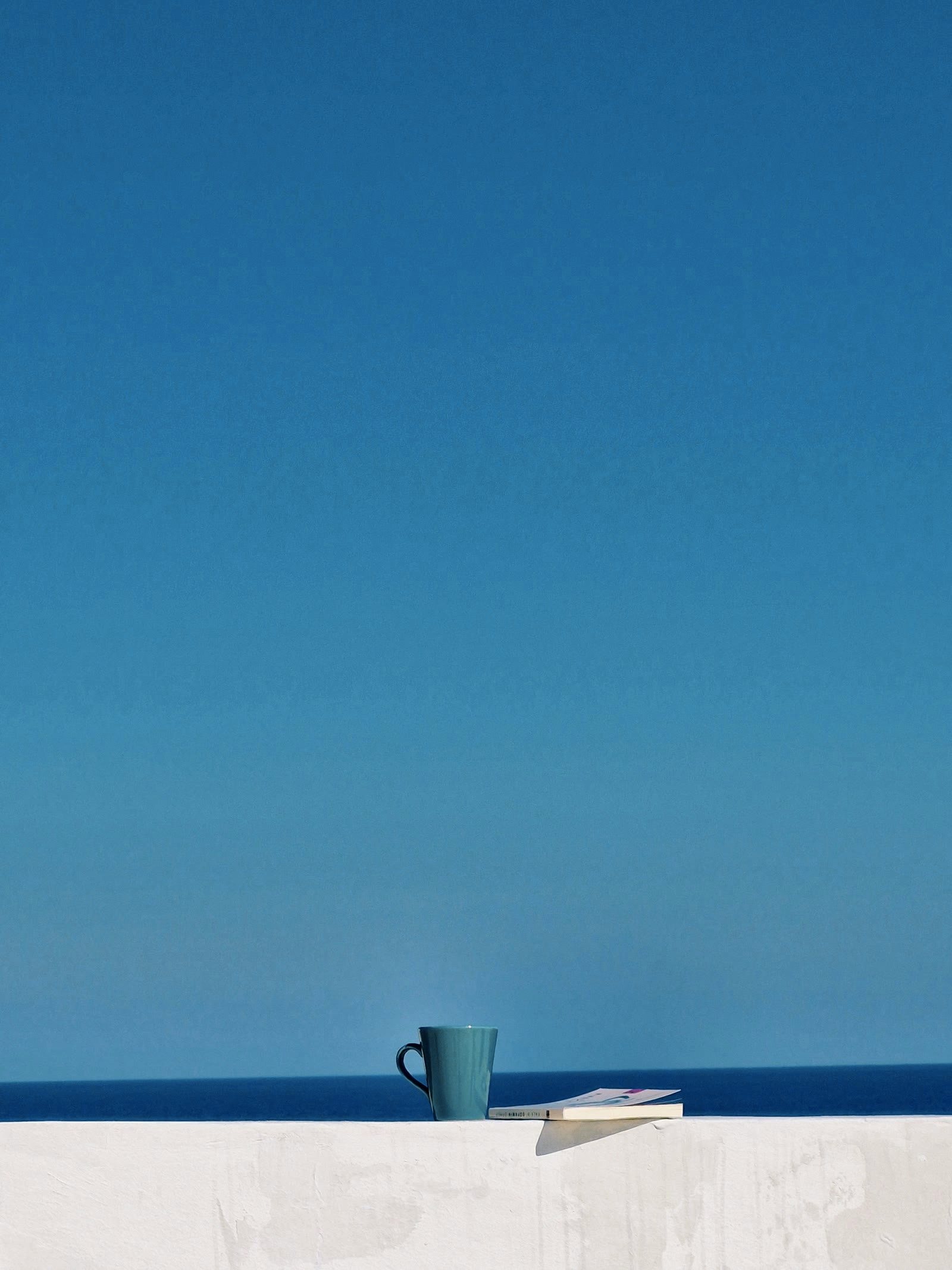A cup and a book on a wall facing the Mediterranean